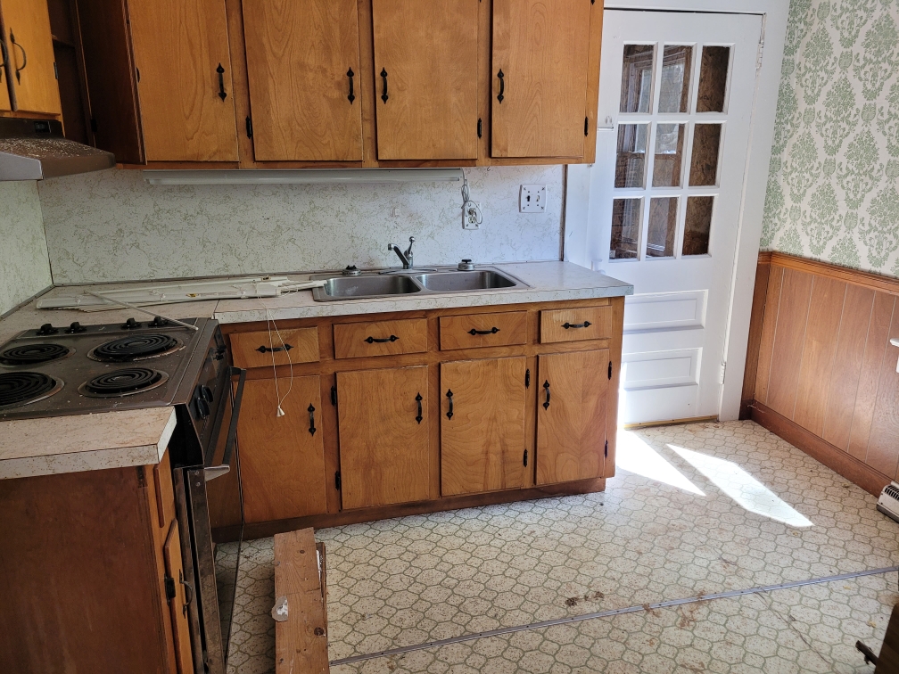 A before photo of Emily's kitchen with outdated cabinets in need of replacing