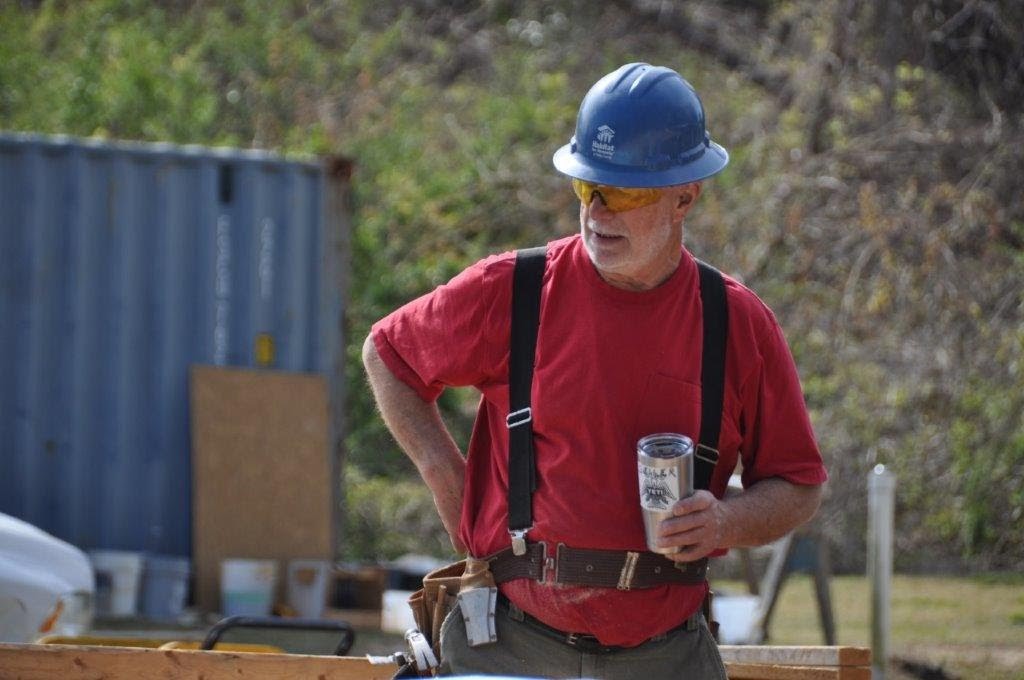 Si Seiler holding a Yeti mug of water on site wearing a blue hard hat