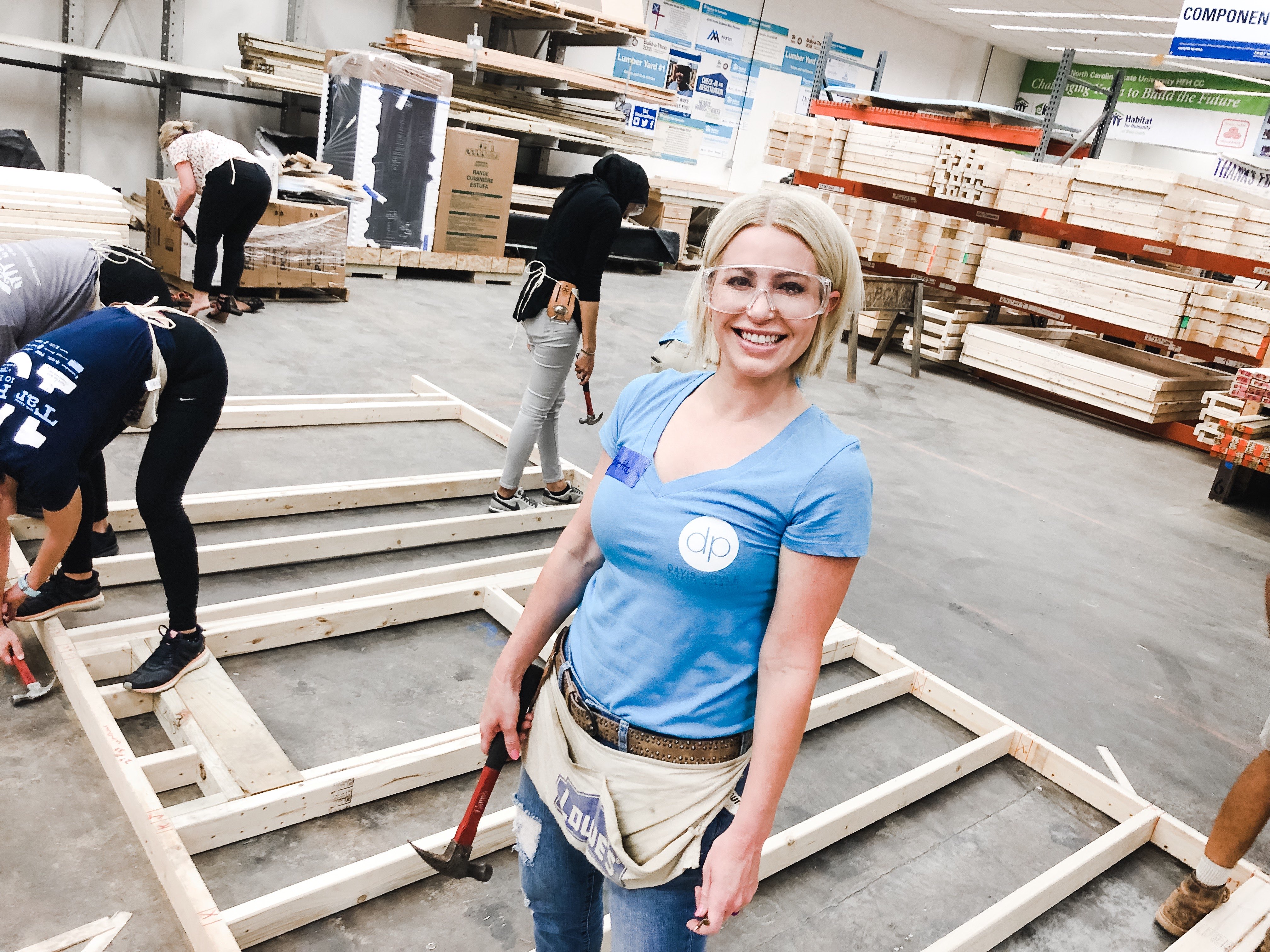 Habitat Wake Women Build board chair in the warehouse with a hammer