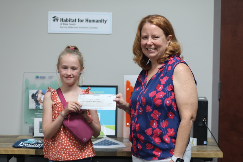 Habitat Wake CEO Patricia Burch standing with Cora June with fundraising check