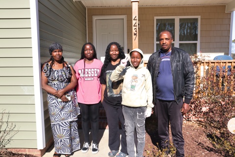 Jacques and his family stand in front of their Habitat Wake home